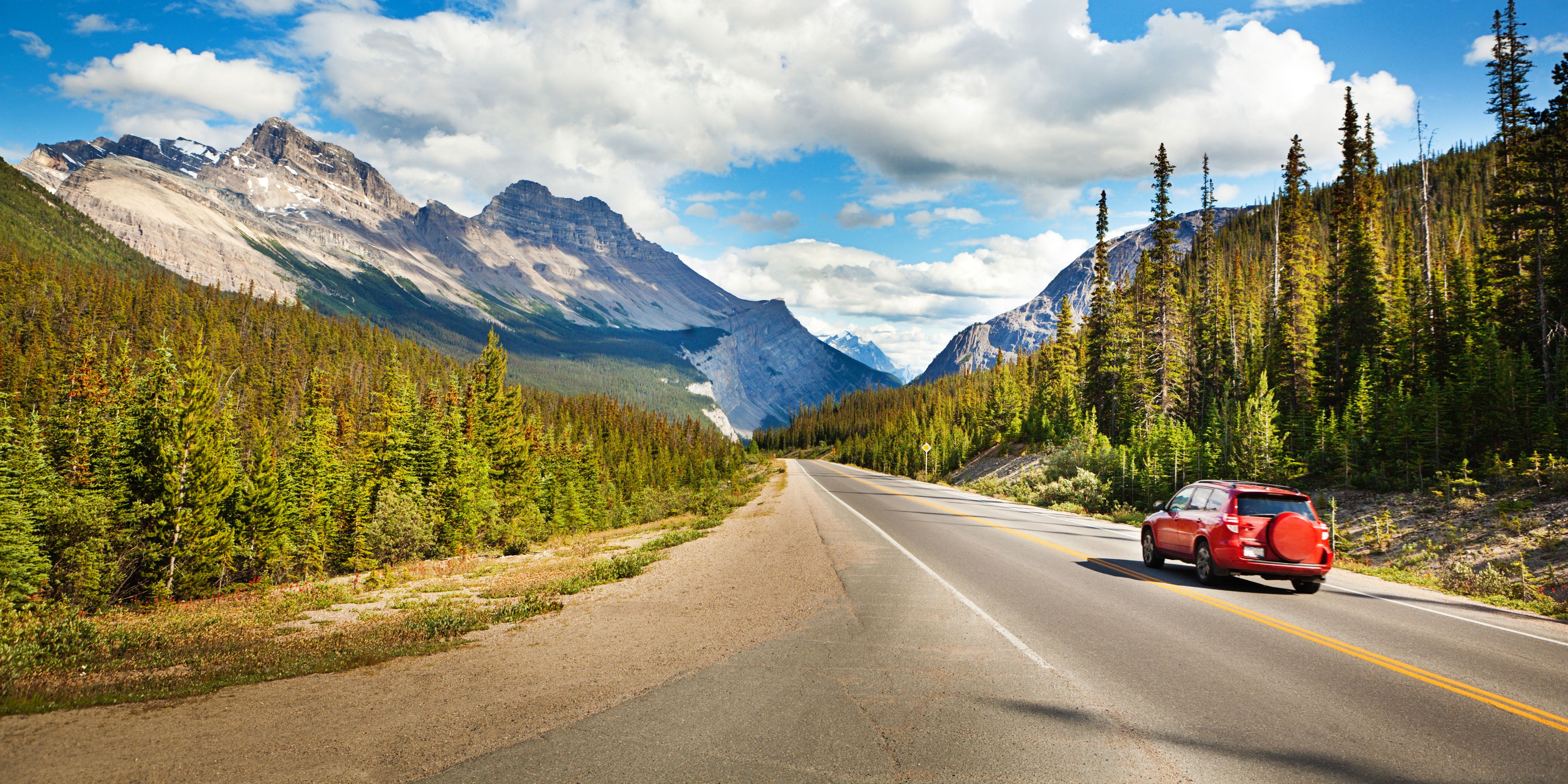 A car driving on a road with mountains in the background