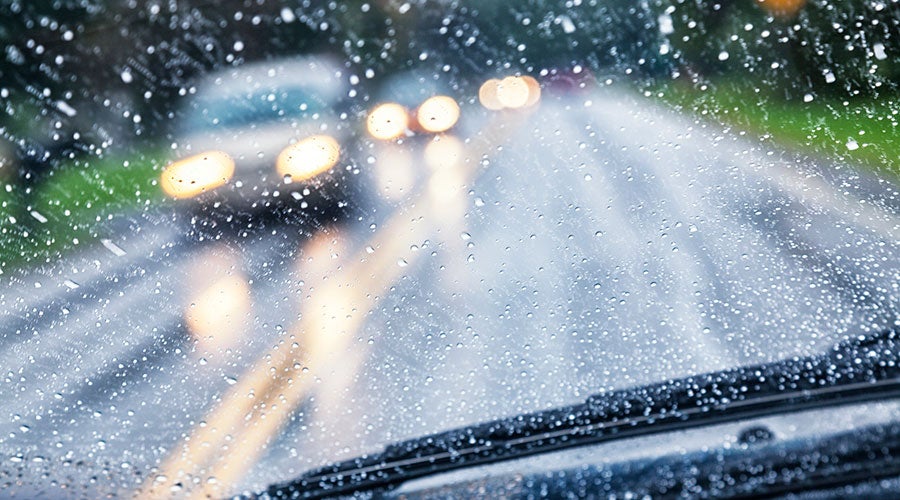 A car driving on a road with rain drops on the windshield