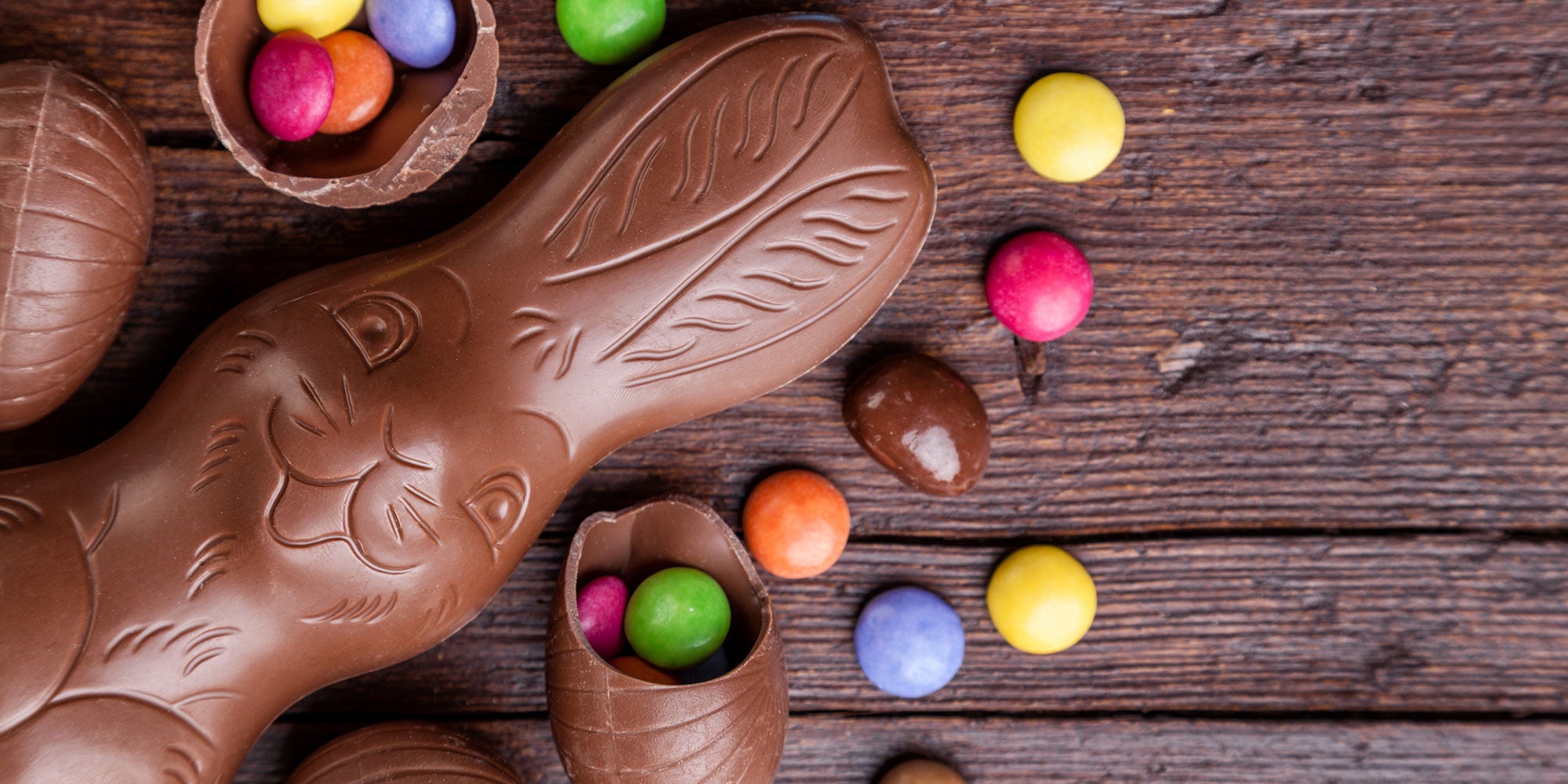 Chocolate bunny shaped chocolate eggs and candy on a wood surface
