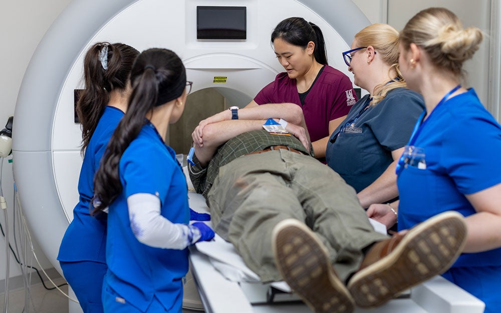 A group of people around a man lying on a scan machine