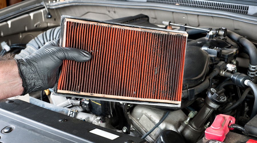 A hand holding a dirty air filter