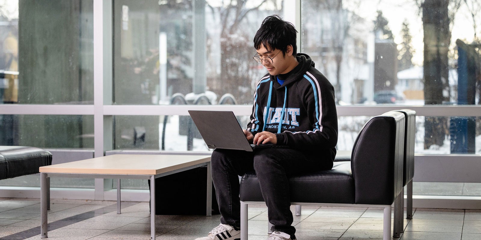 A man sitting on a chair using a laptop