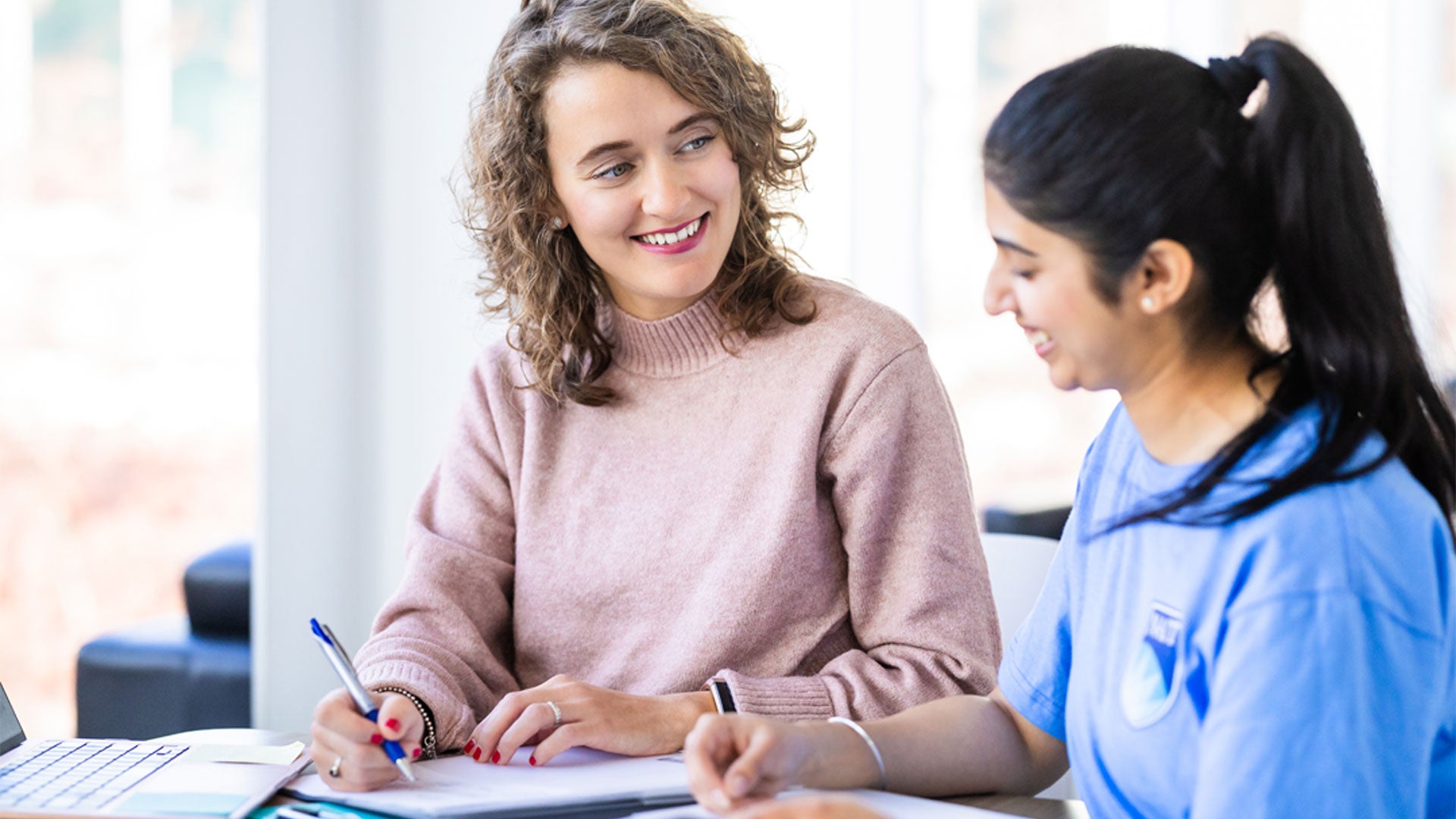 A woman smiling while writing on a piece of paper