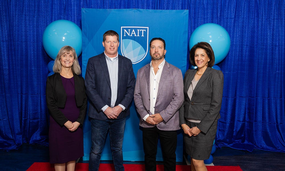 A group of people standing in front of a blue backdrop