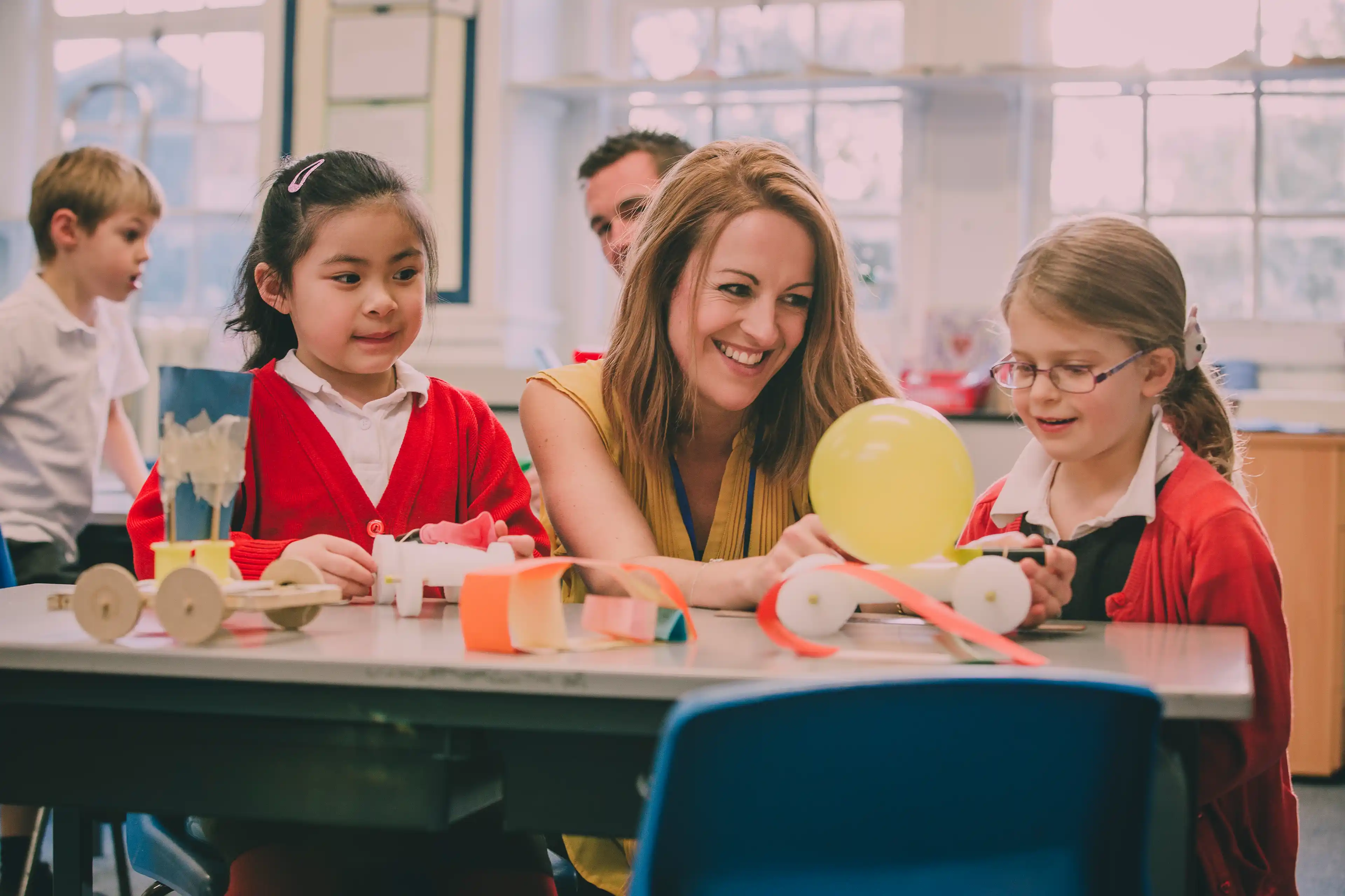 Female teacher in classroom demonstrating STEM experiment with two pupils