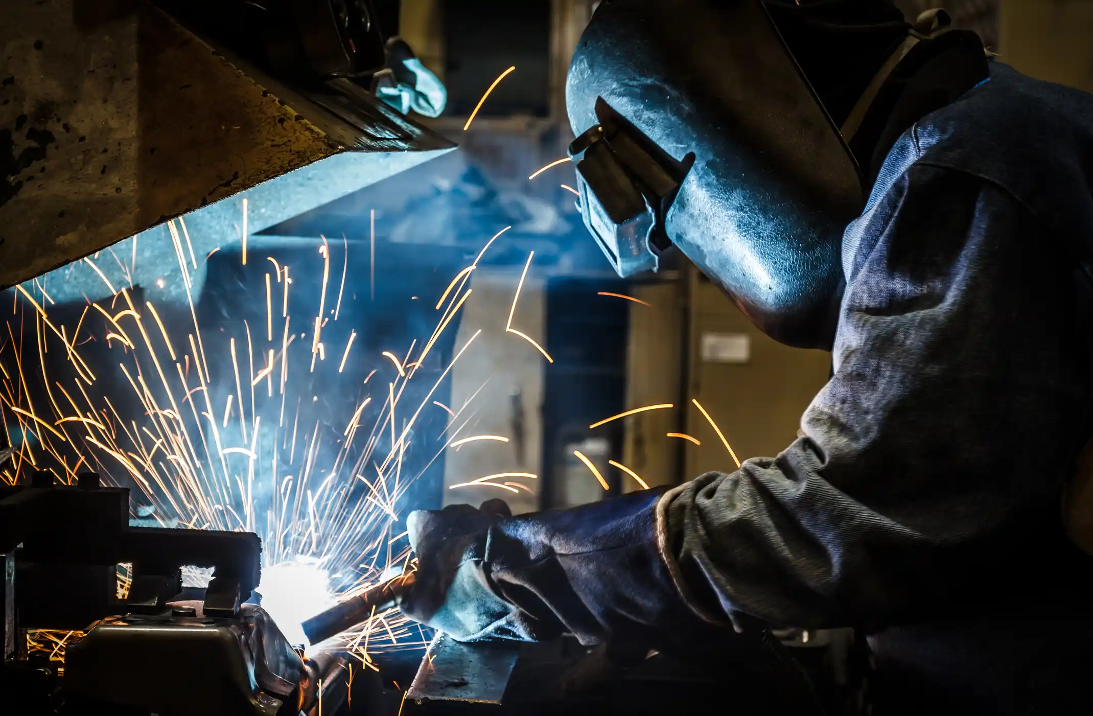 Welder wearing a safety mask with sparks flying.