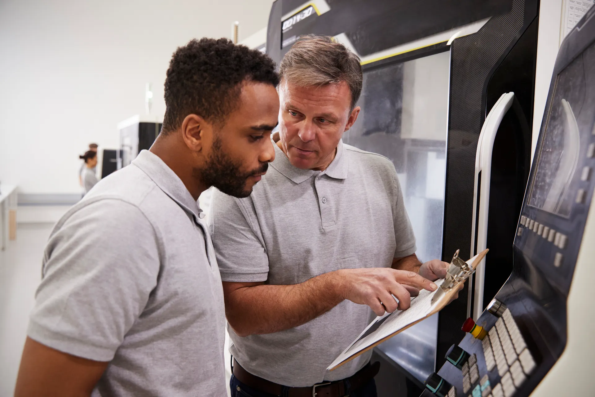 Engineering apprentice in employer collared shirt speaking in a lab with employer