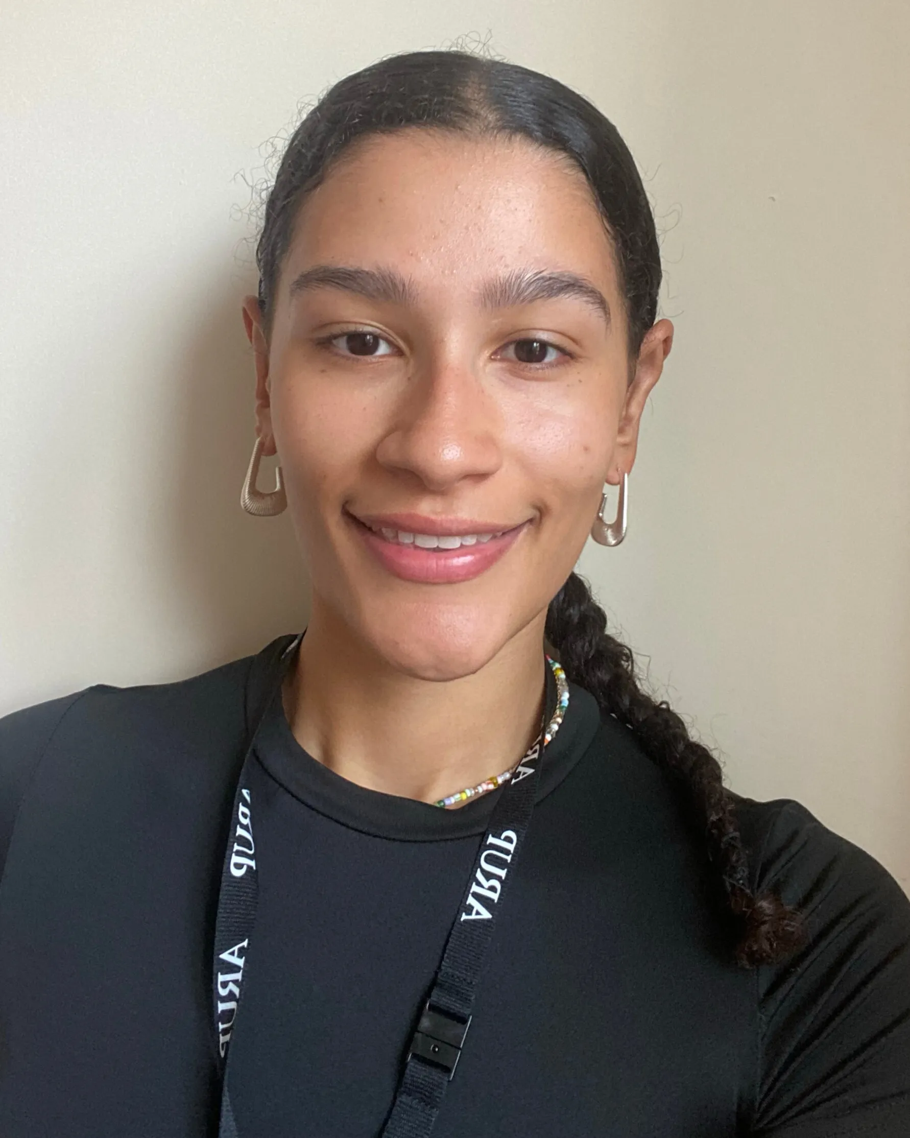 A young woman with dark hair stands against a white background