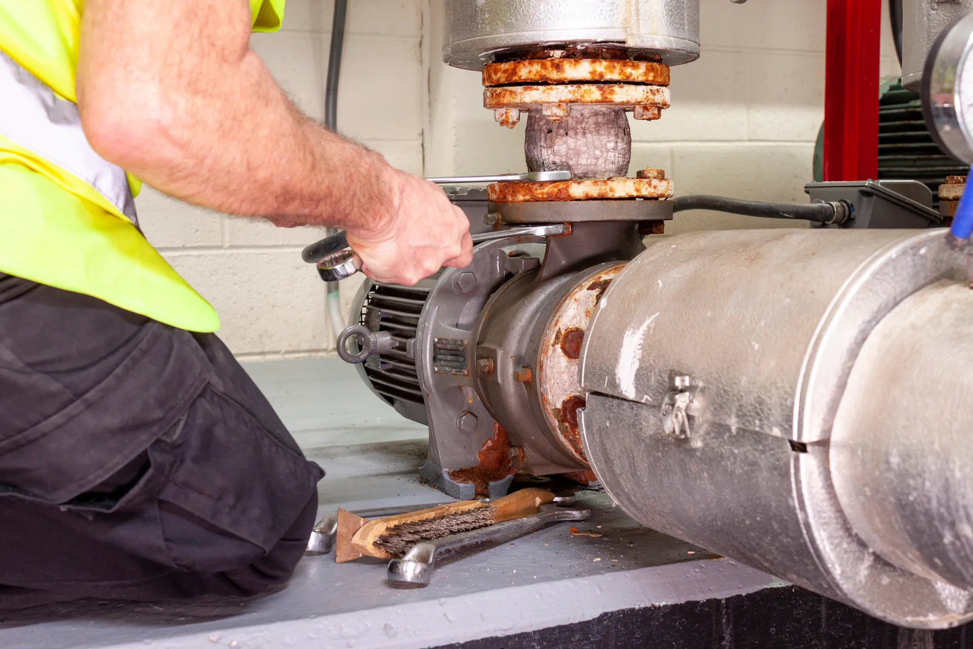 Mechanical engineer in hi viz vest removing a pump joint