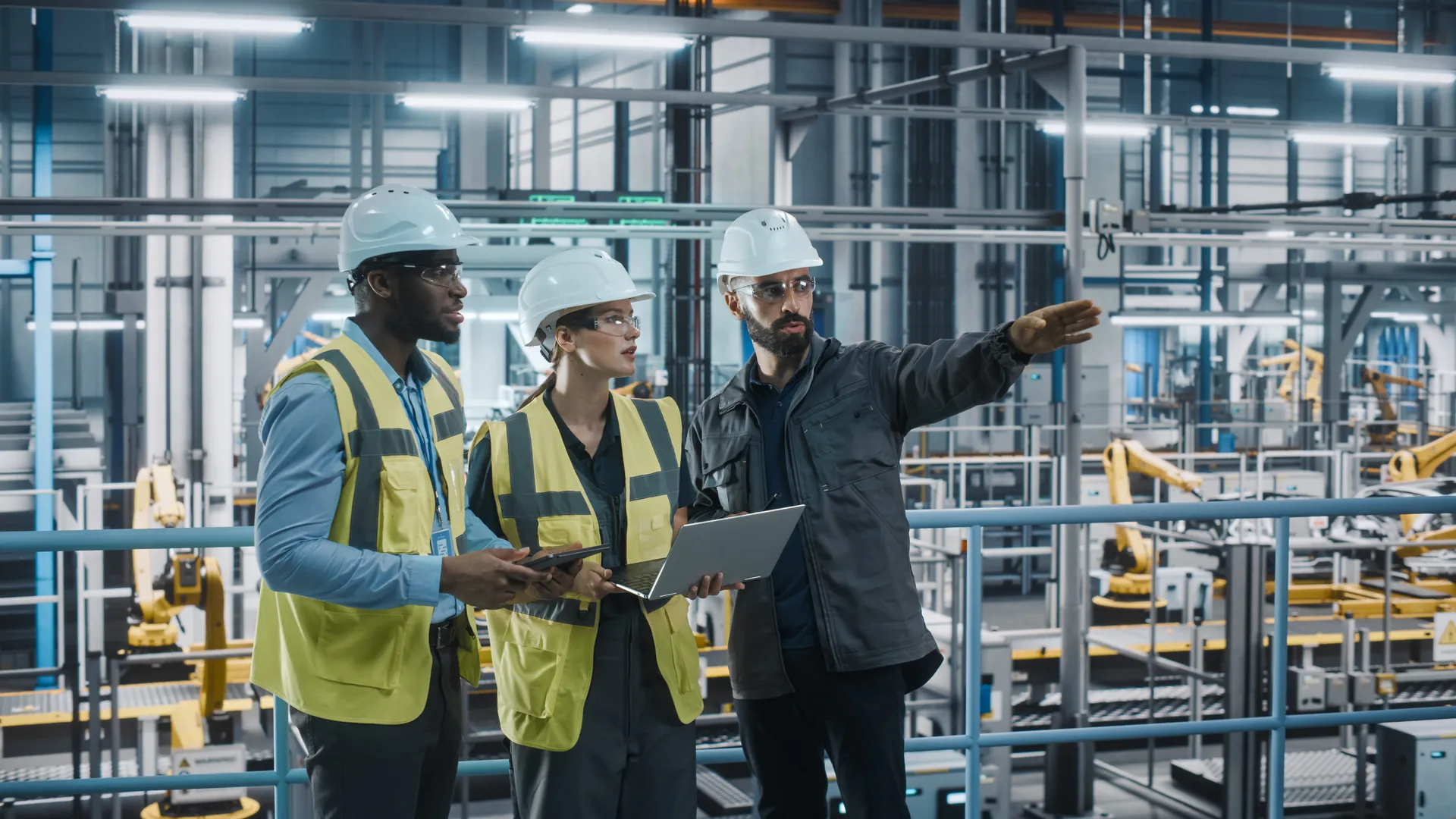 Young Diverse Team of Car Factory Specialists Working on Laptop and Tablet Computers. Engineers Discussing Automotive Industrial Manufacturing Technology on Modern Vehicle Assembly Plant.