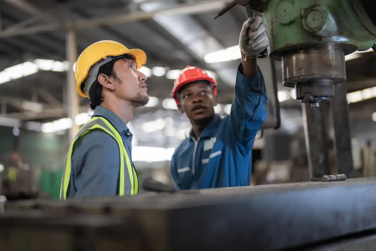 Two men in a factory working at steel heavy machine