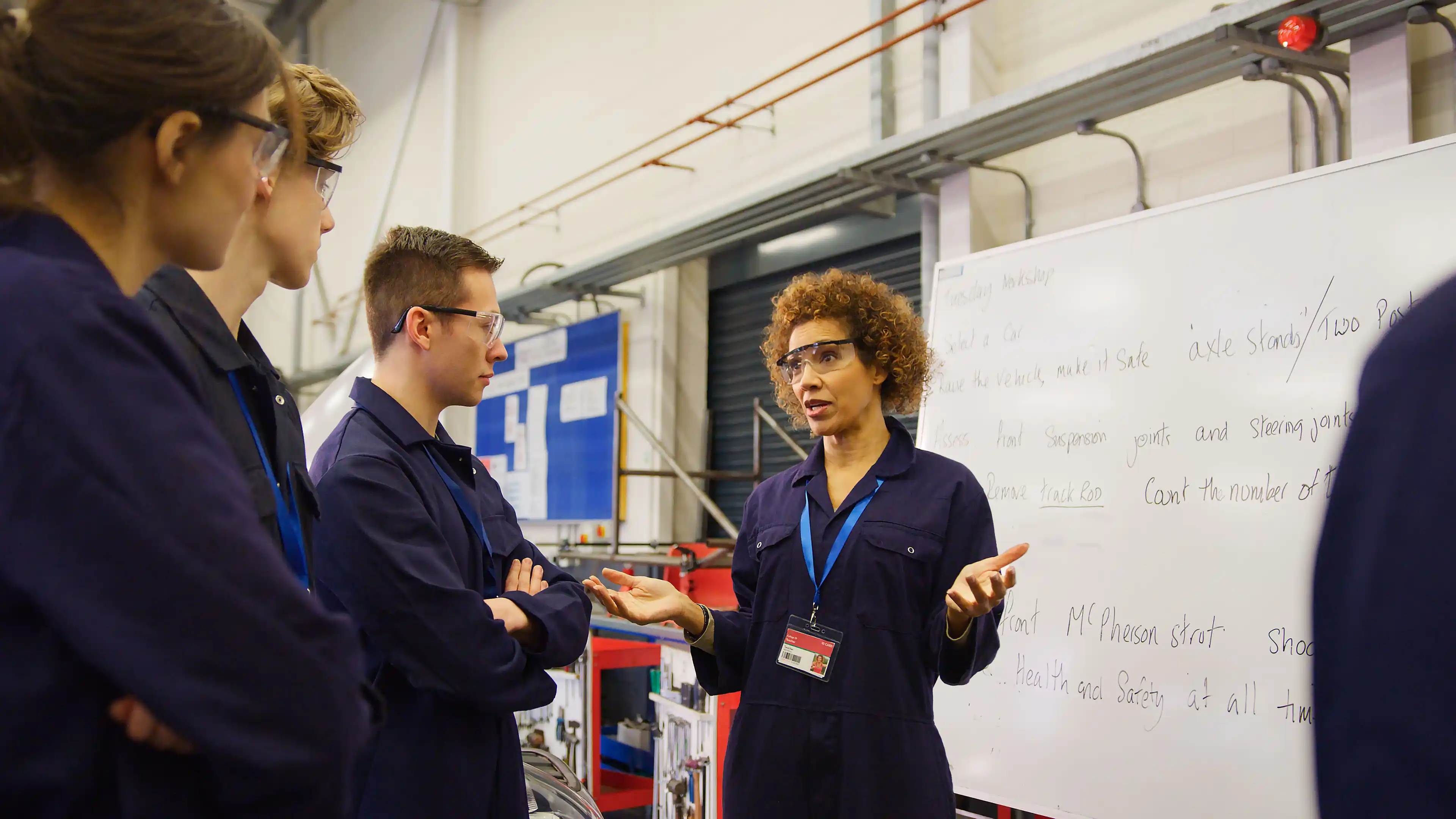Tutor working with engineering apprentices in a workshop.