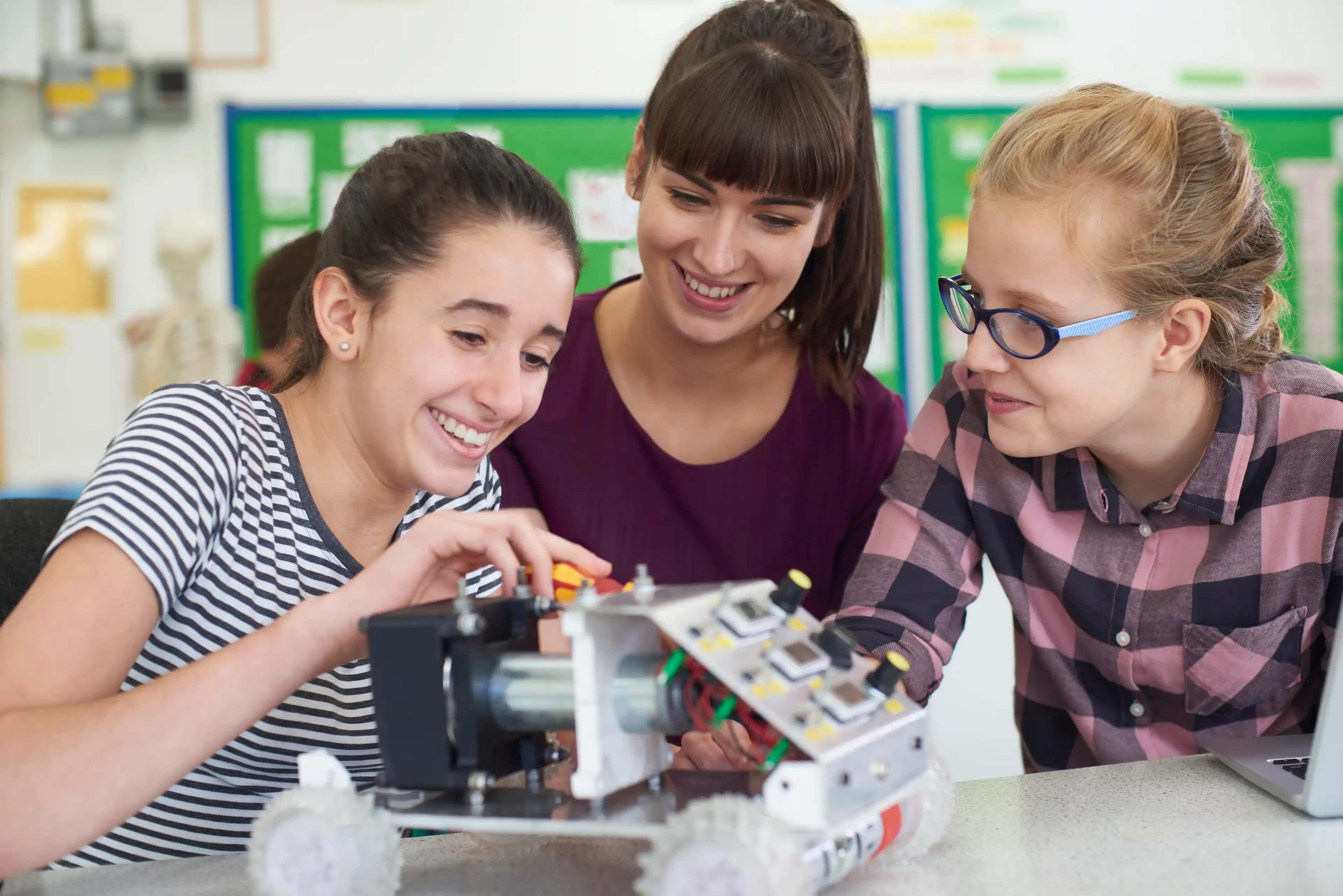 Teacher Talking To Female Pupils Studying Robotics In Science Lesson