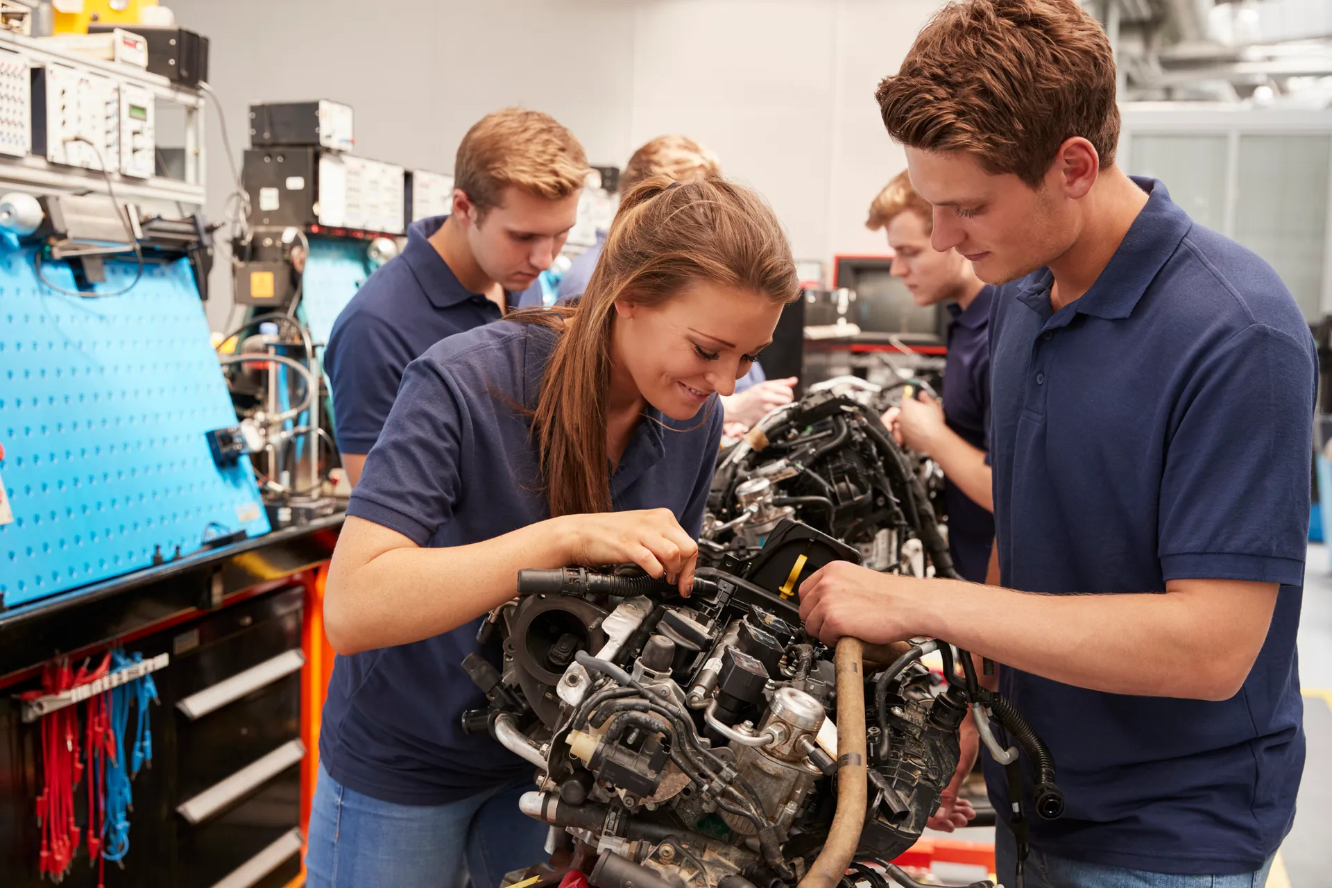 Apprentice car mechanics working on an engine