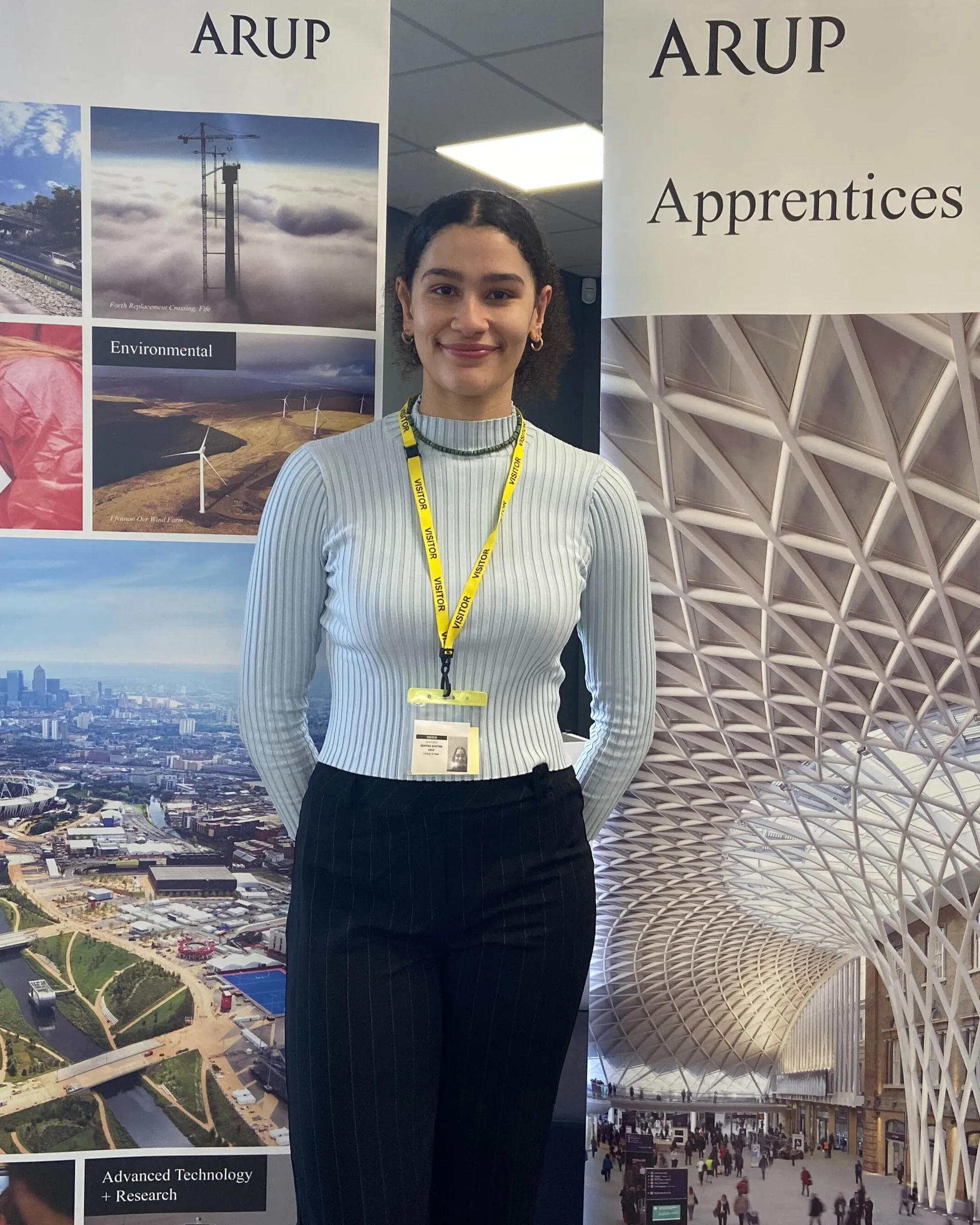 A dark-haired woman stands in front of two roller banners displaying information about a company