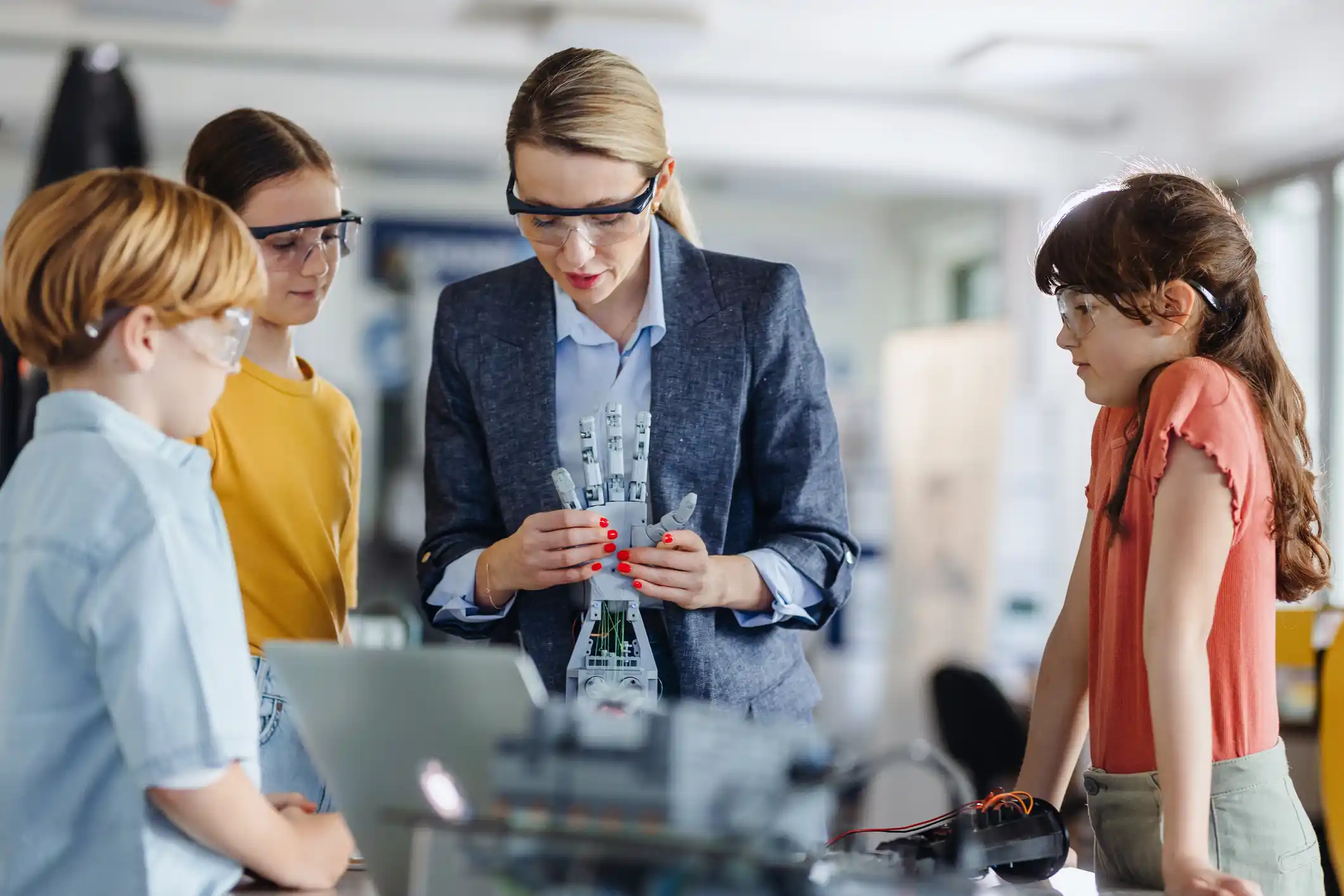 Young students building robot in classroom with female teacher