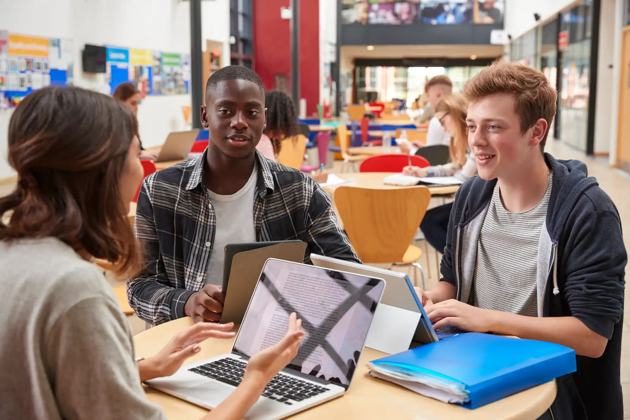 Teacher Talks To Students In Communal Area Of College Campus