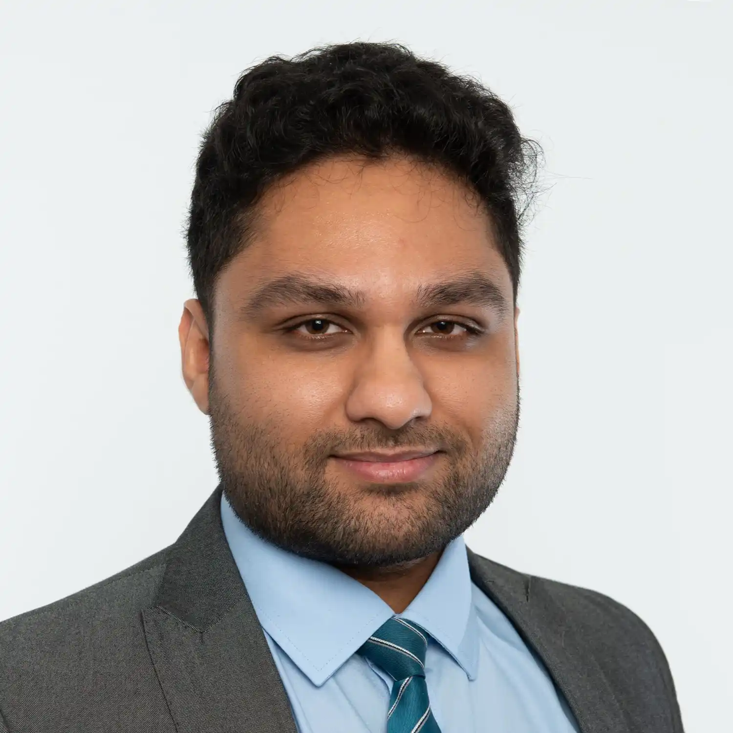 A dark haired man wearing suit jacket, blue shirt and green tie