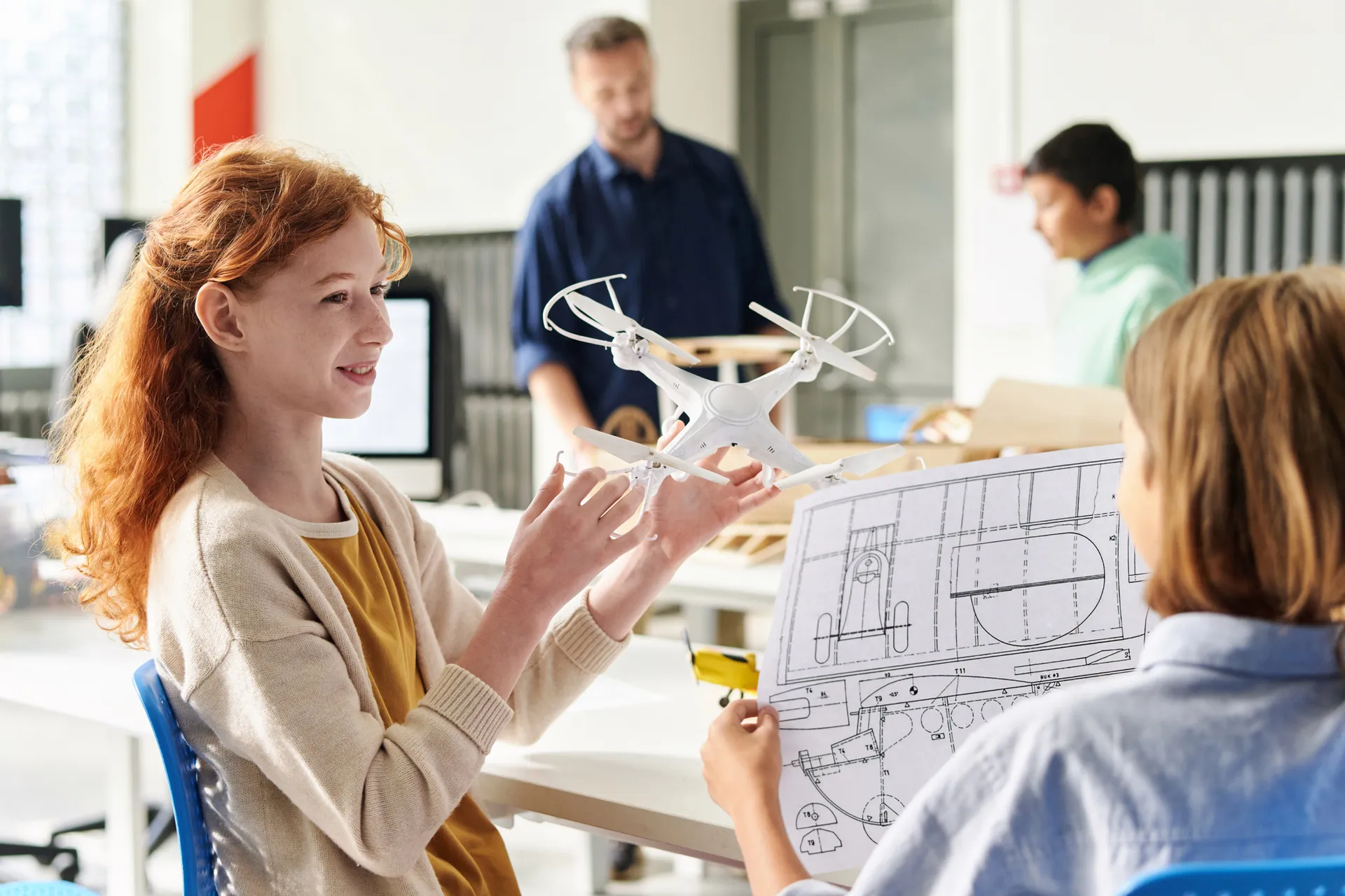 Young female student in engineering classroom holding a drone