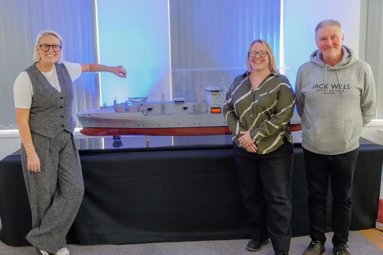 Steph McGovern at iconic Harland & Wolff shipyard, standing in front of a ship model with Kat Thorne, Head of Talent and Culture, and Brian Welsh, also known as Mr. Apprentice.