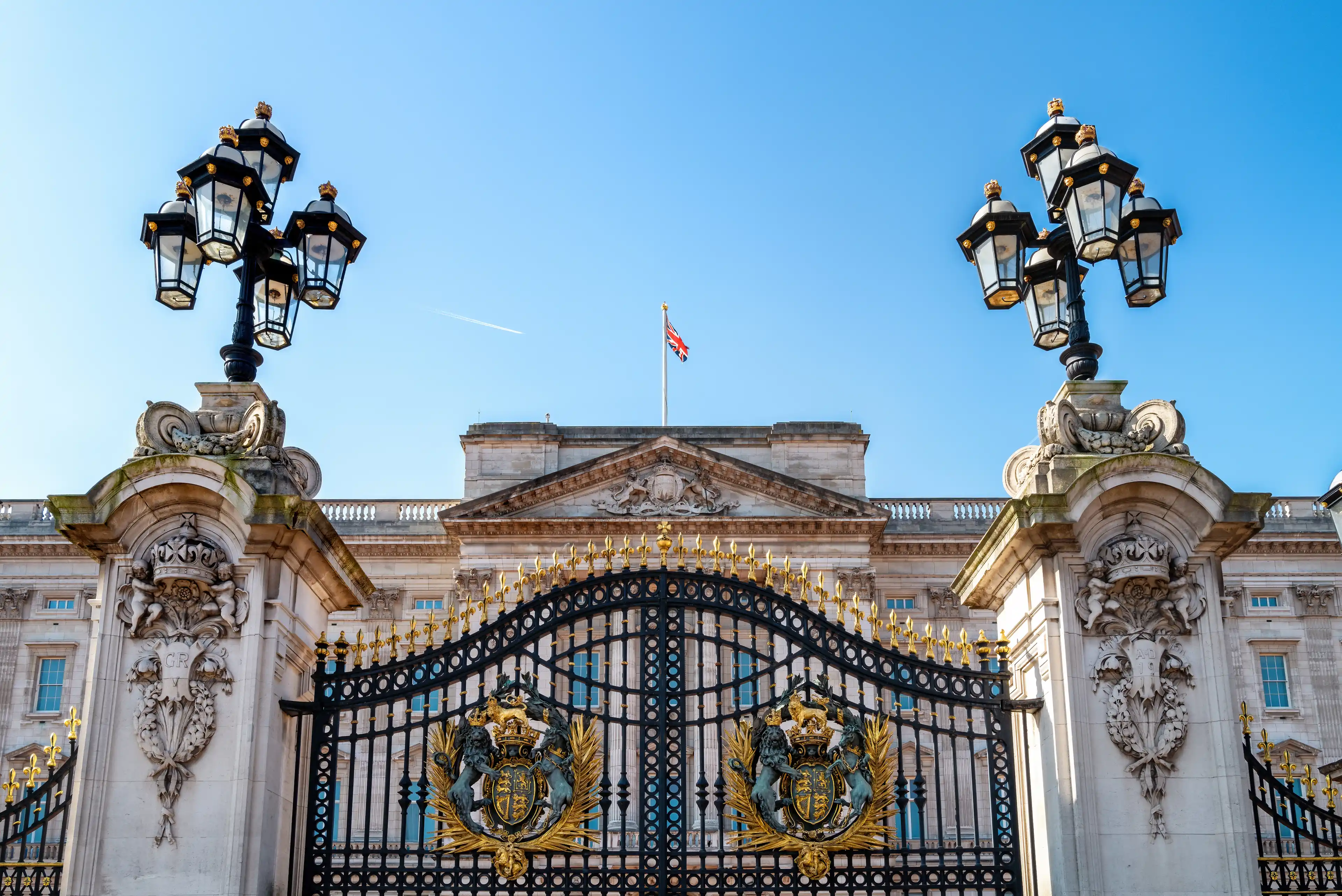 Buckingham Palace, London, with coat of arms and ornate lanterns.