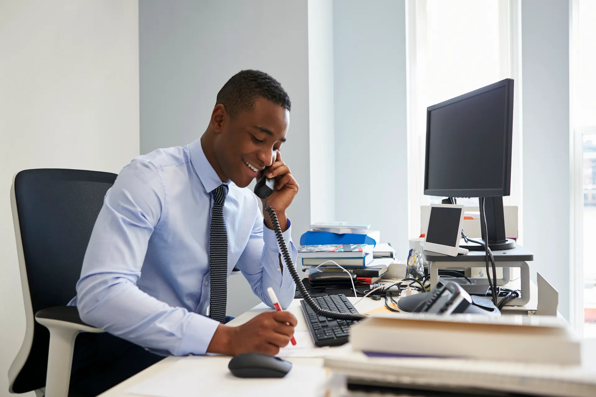 Young black businessman using the phone at his office desk
