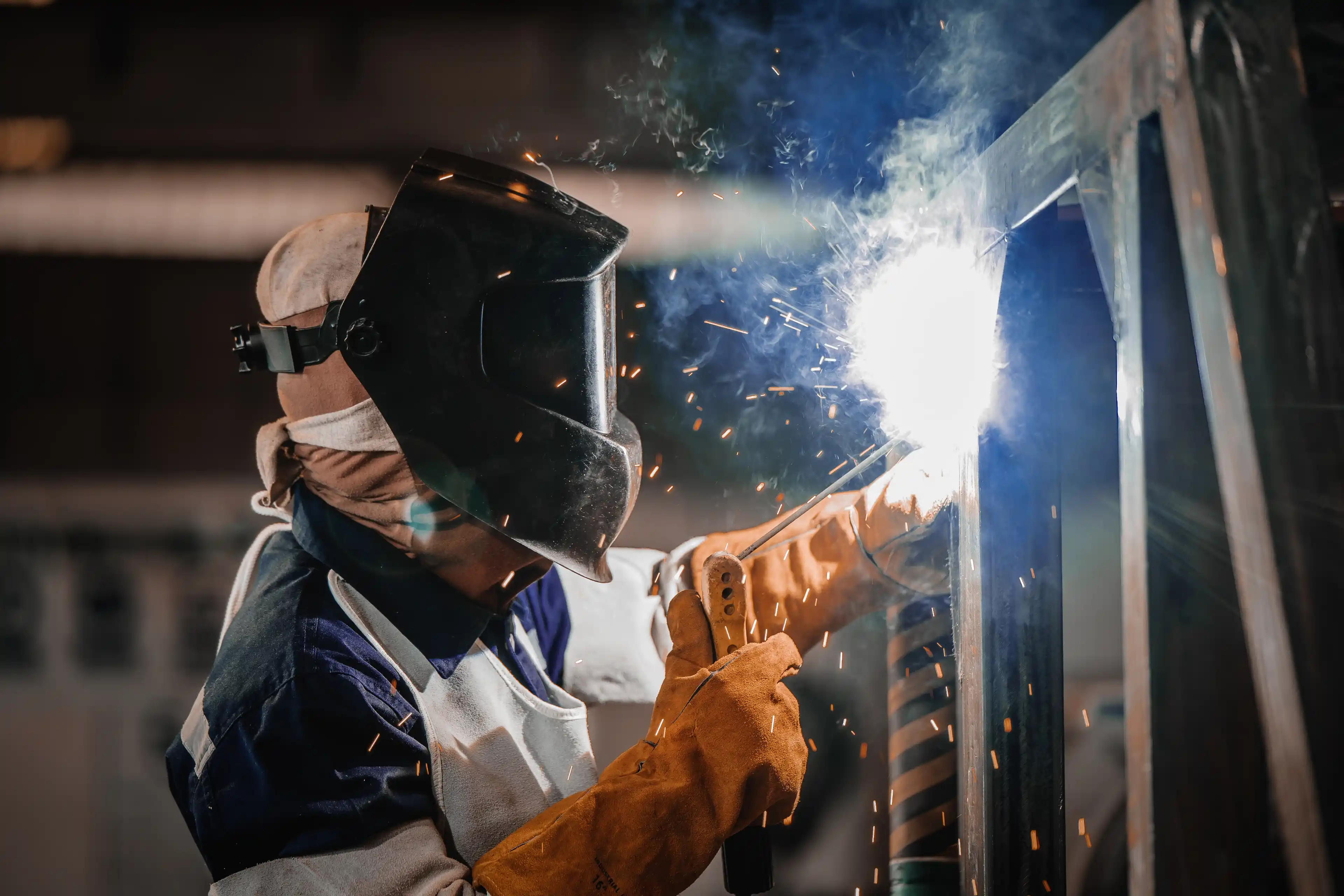 Industrial worker welding steel structure with sparks.