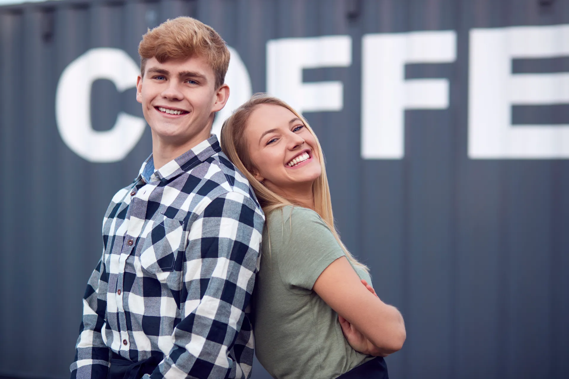 Portrait Of Male And Female Interns At Freight Haulage Business Standing By Shipping Container
