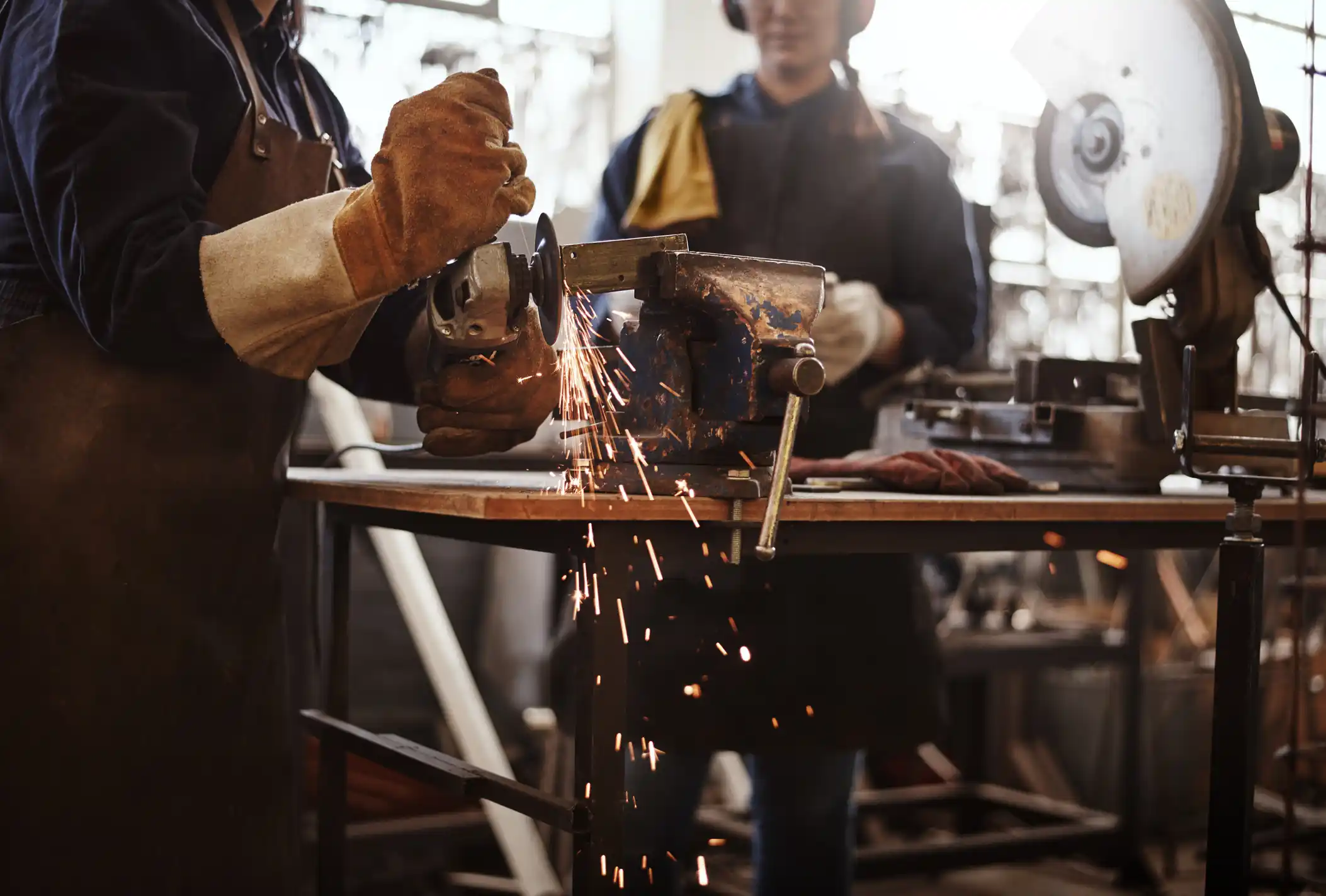 Cropped shot of two unrecognizable young female artisans using an angle grinder in their workshop