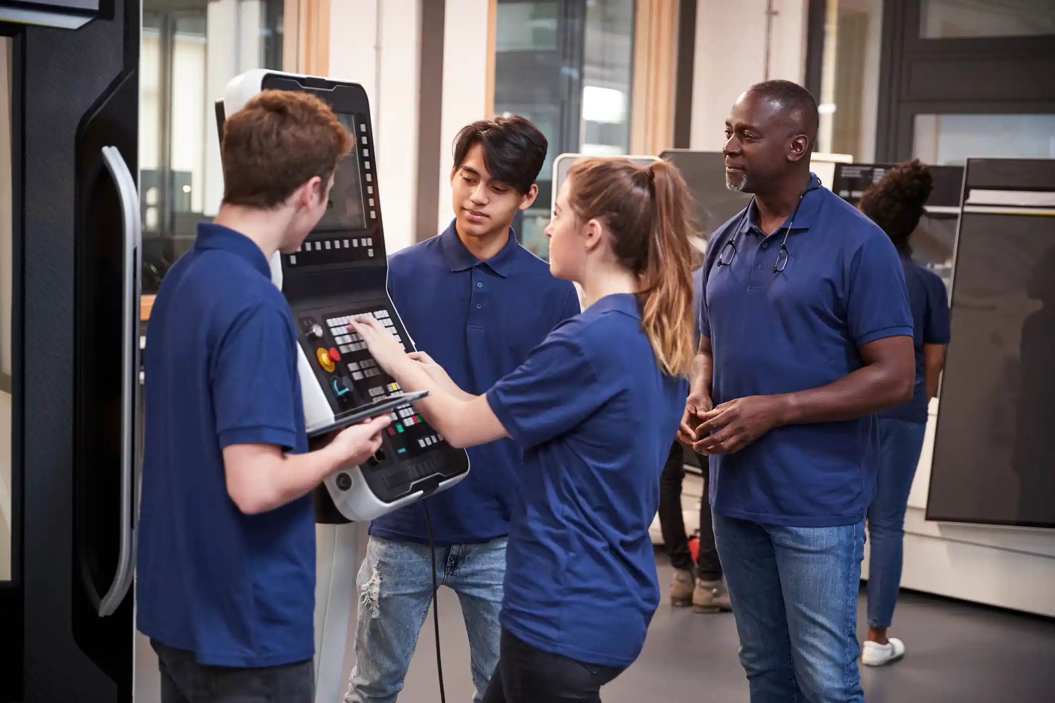 Engineer showing apprentices how to use CNC tool