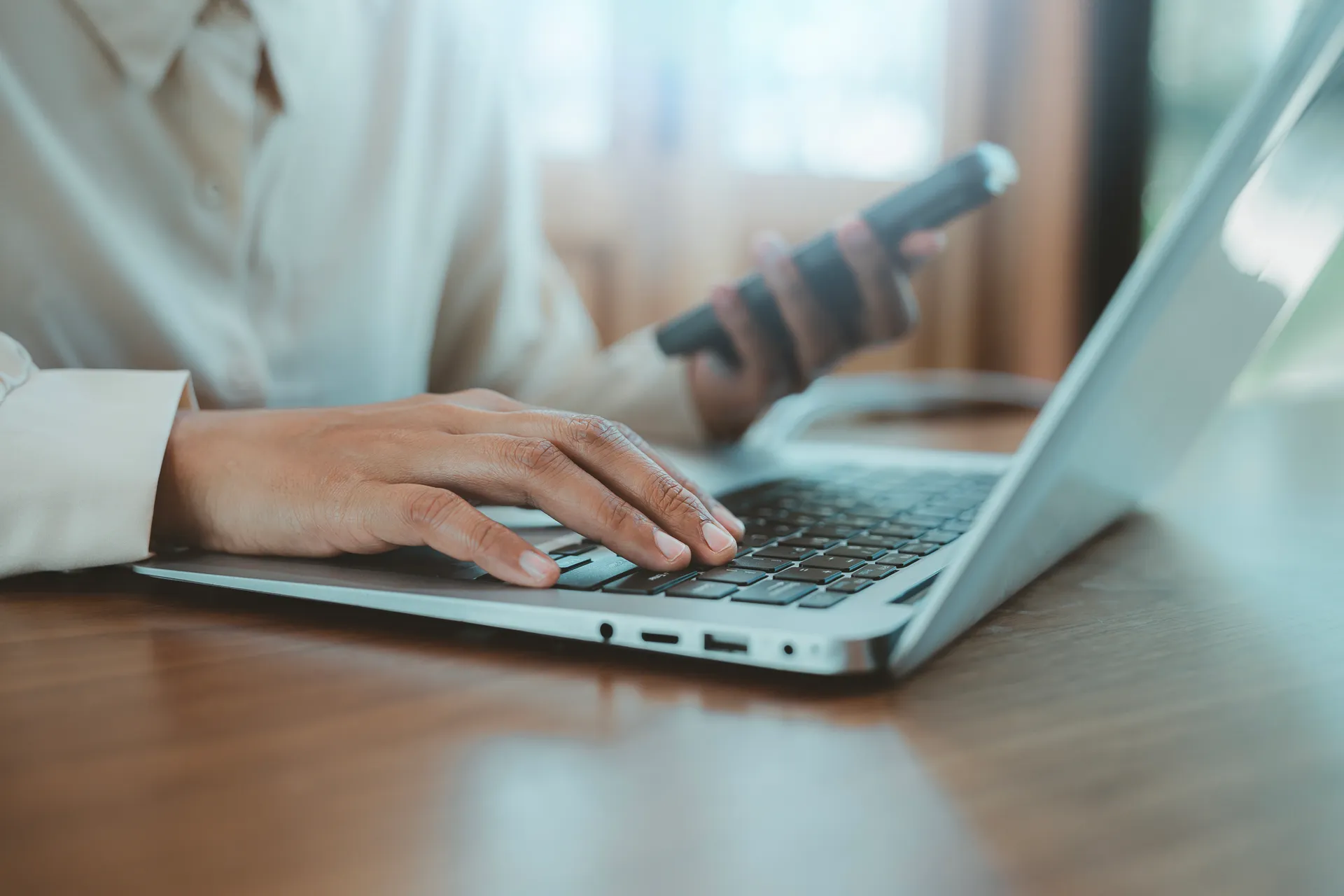 multitasking person hands typing laptop keyboard holding smartphone remote work efficiency internet business data communication