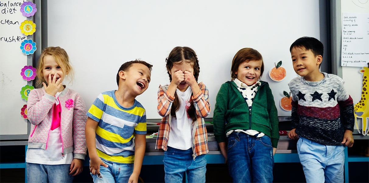 Een groep jonge kinderen aan het lachen in de klas
