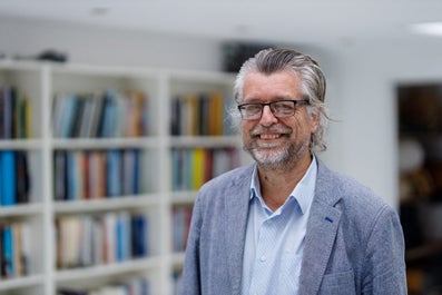 Een man in een pak en een bril glimlacht