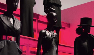 Mannequins dressed in black with a red lit background.