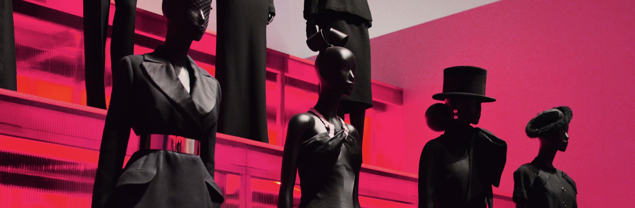 Mannequins dressed in black with a red lit background.