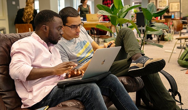 Twee studenten vergelijken notities op de laptop en mobiele telefoon