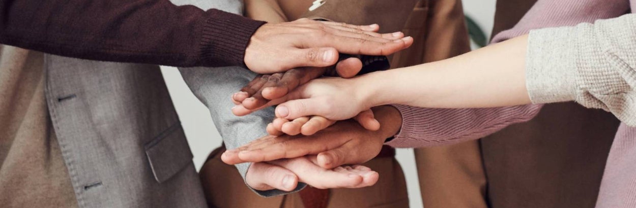 Een groep mensen die hun handen op elkaar leggen