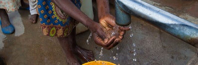 Iemand wast haar handen onder een primitieve kraan