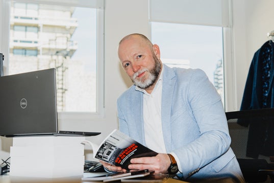 Criminoloog Jasper van der Kemp achter een bureau met een boek in zijn handen