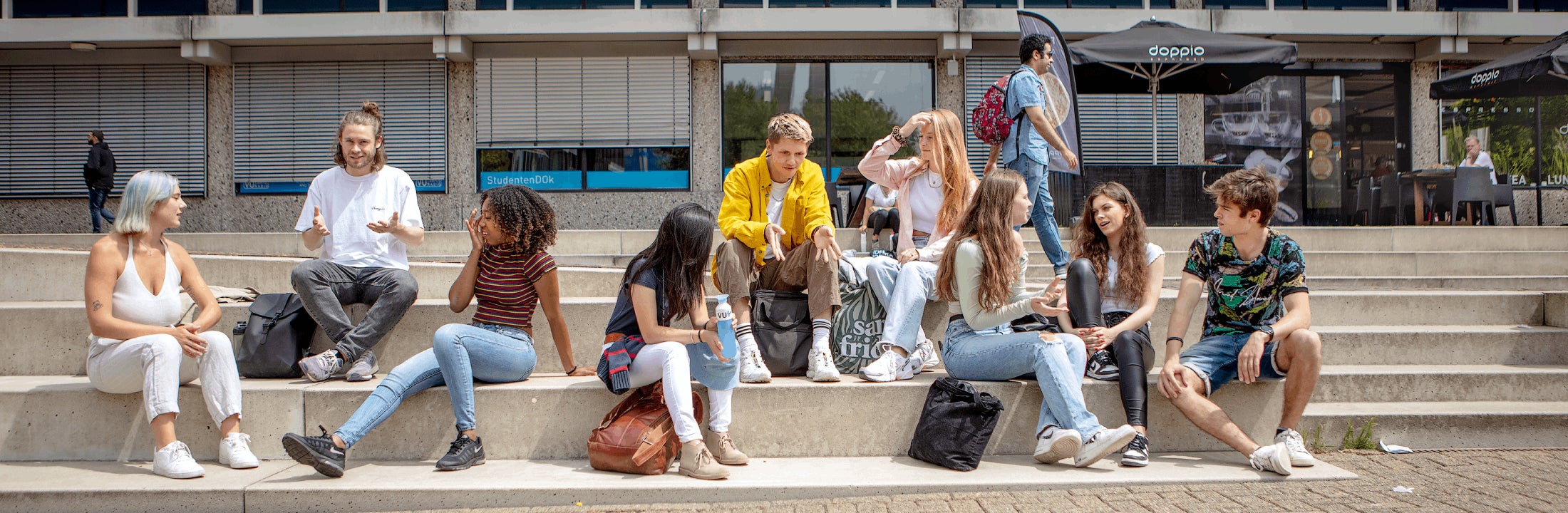 A group of students sit outside on the stairs on the VU campus