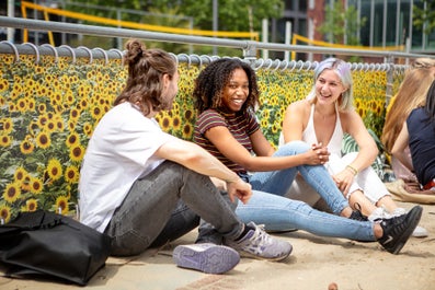 Drie studenten zittend op de grond voor het volleybalveld op de de VU campus