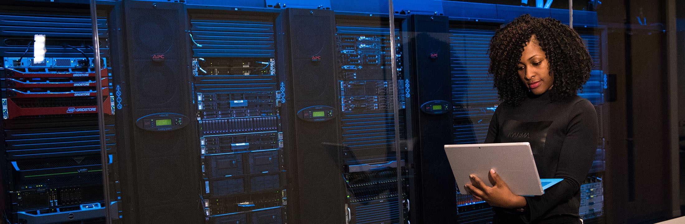 women looking at laptop next to data servers