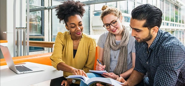 Drie alumni kijken samen in een boek
