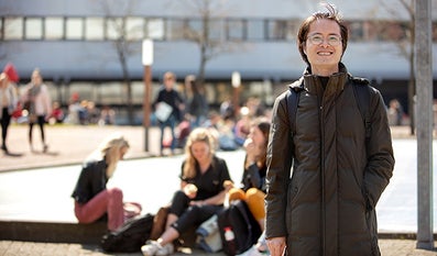 Student op de VU campus met andere studenten op de achtergrond