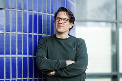 Een man leunt tegen een muur