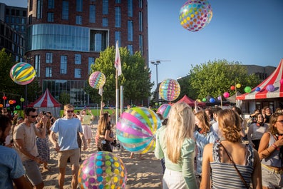 students on campus square playing with big plastic balls