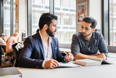 Twee studenten buigen zich over studieboeken.