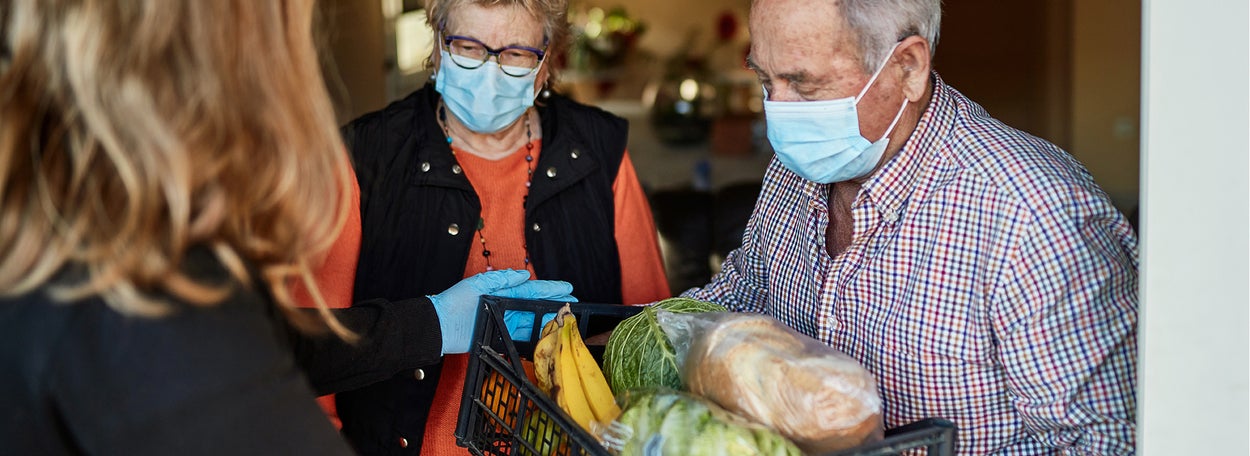 Een man en een vrouw met mondkapjes op nemen een box met boodschappen in ontvangst