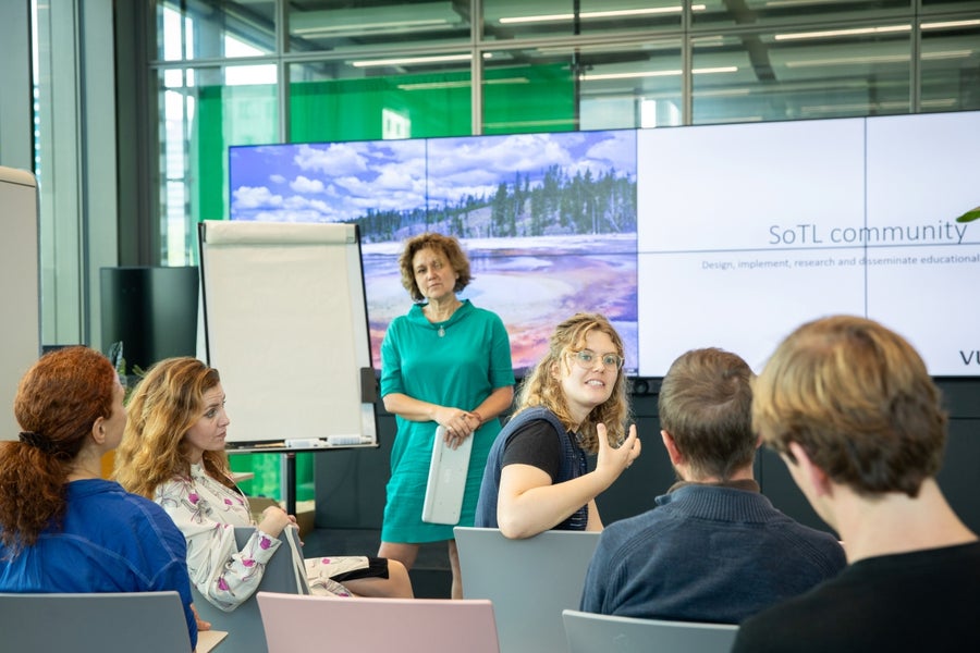 Een groep mensen is met elkaar in gesprek terwijl de gespreksleider toekijkt