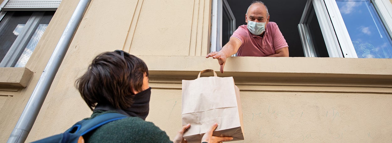 A man takes a bag of groceries from someone through the open window